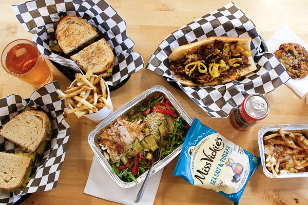 A full spread of Tom's Deli sandwiches, chips, drinks, fries, poutines.